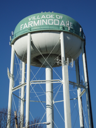 A tall water tower featuring a prominent sign attached to its side against a clear blue sky.